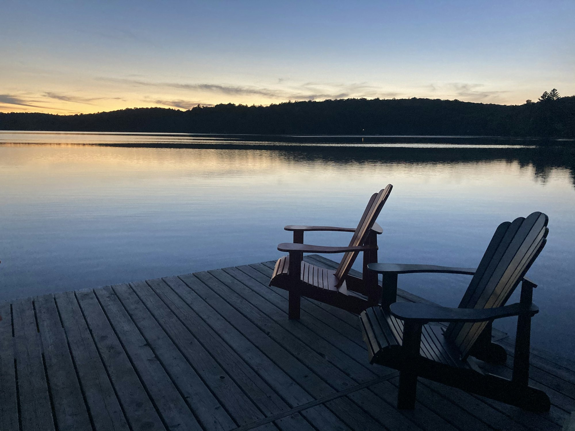 Lakeside dock with two chairs at sunset (representative photo)